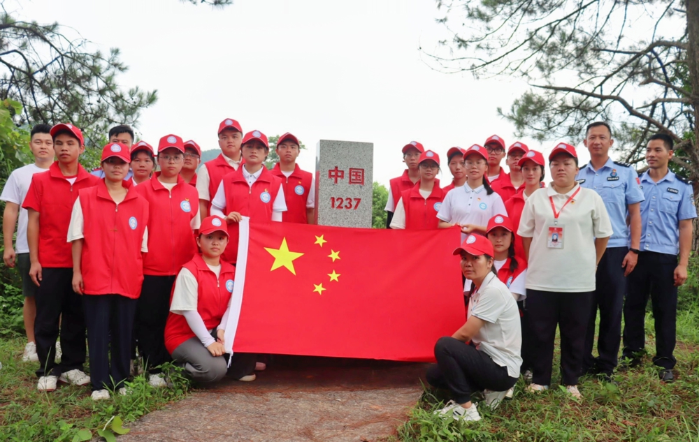 实践服务团队与边防民警们在中越界碑前与国旗郑重合影